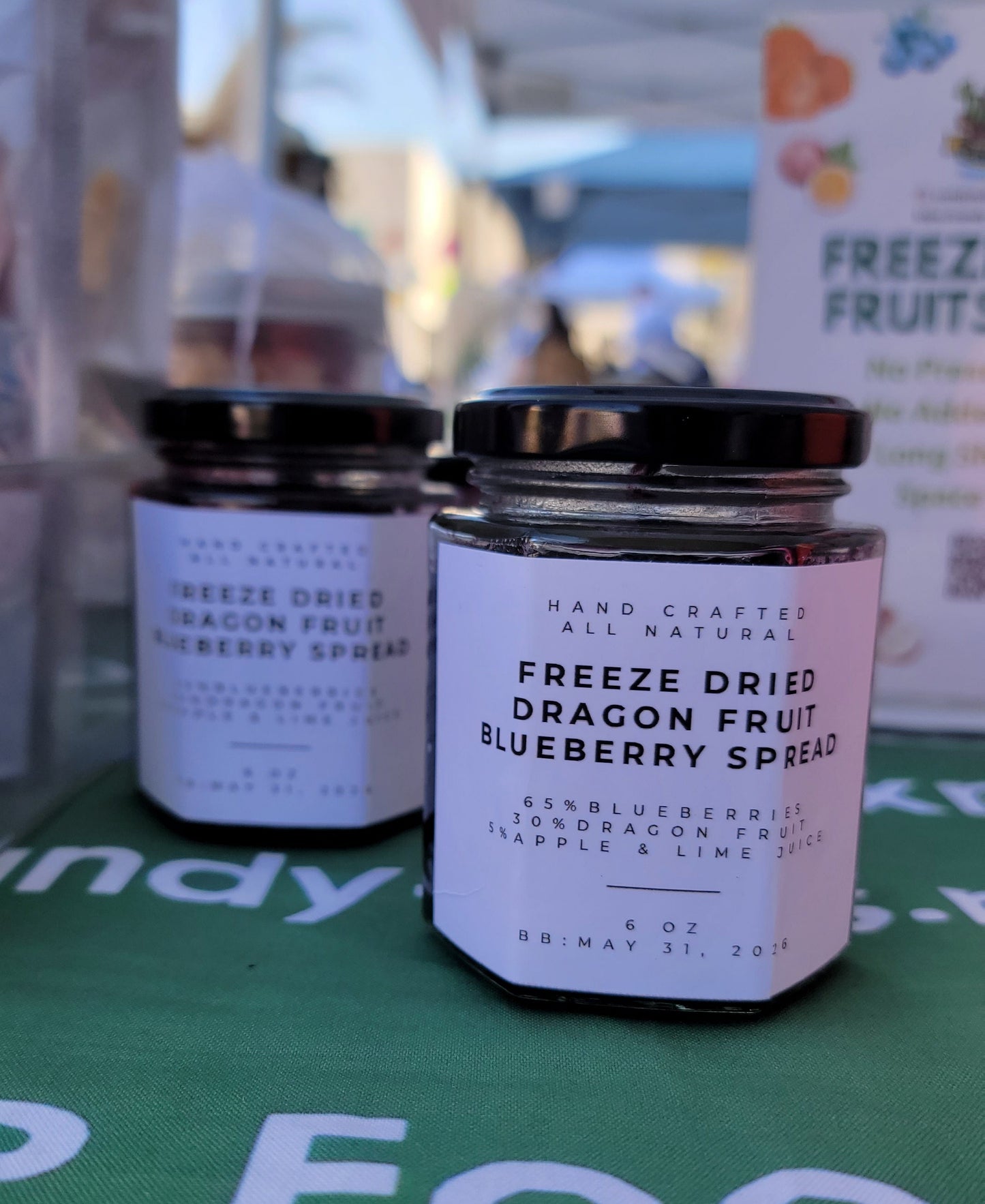 Jars of freeze-dried blueberry spruce on a reflective surface with a green background